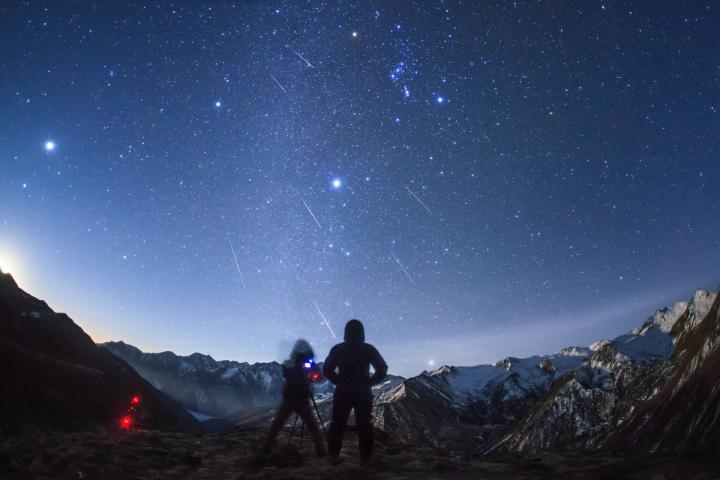 two people watching and photographing the geminid meteor shower in december