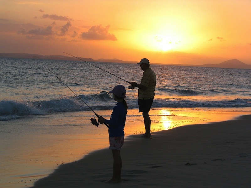 Apa és lánya horgászik a tengerparton