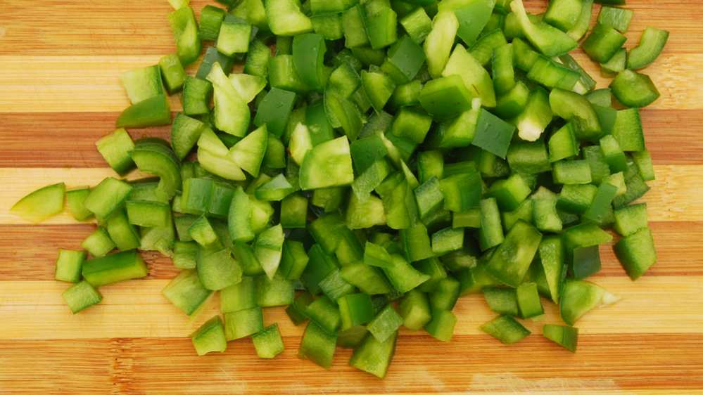 chopped green peppers on a wooden cutting board