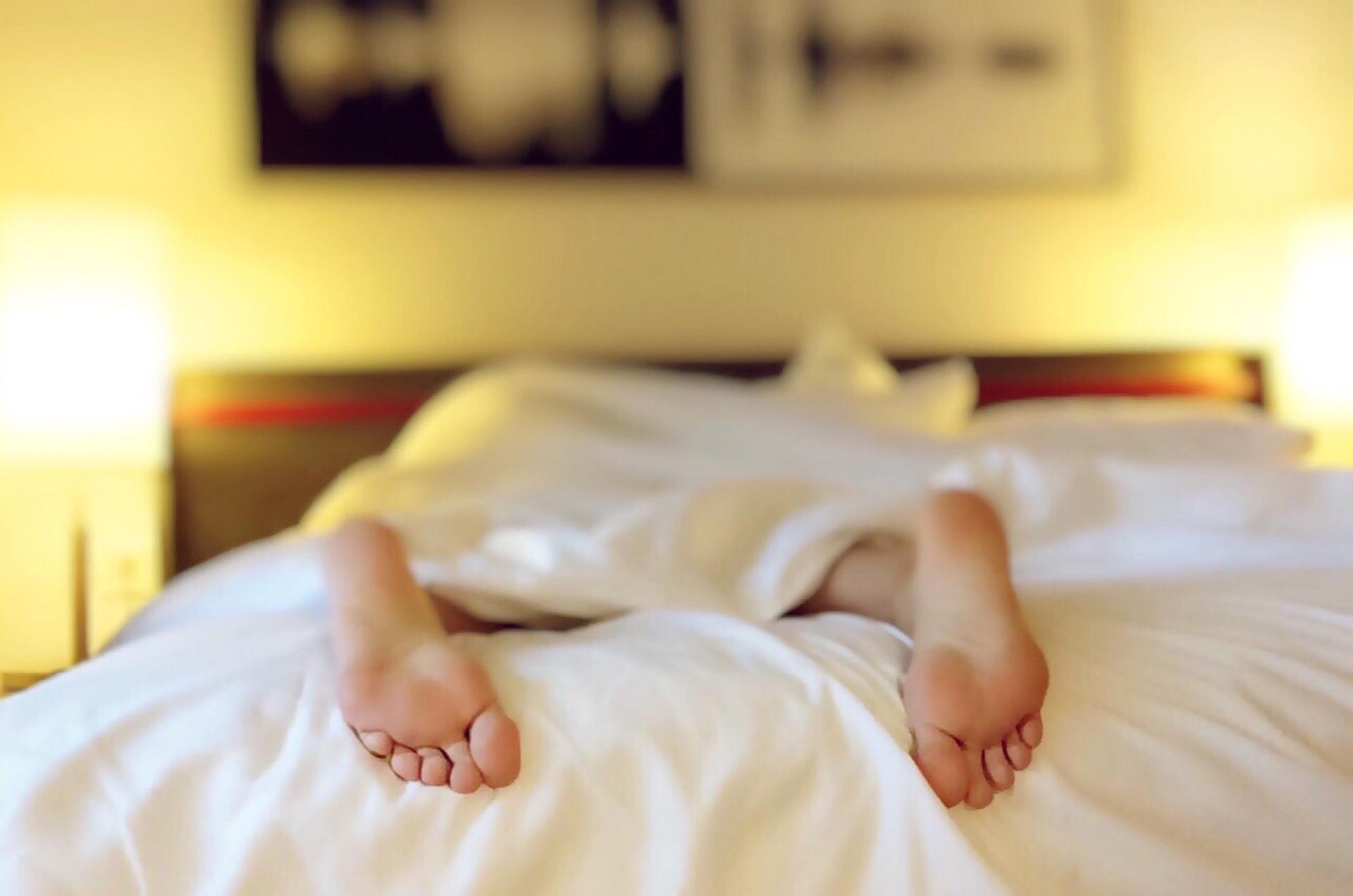Person asleep in bed, feet sticking out from under the sheets