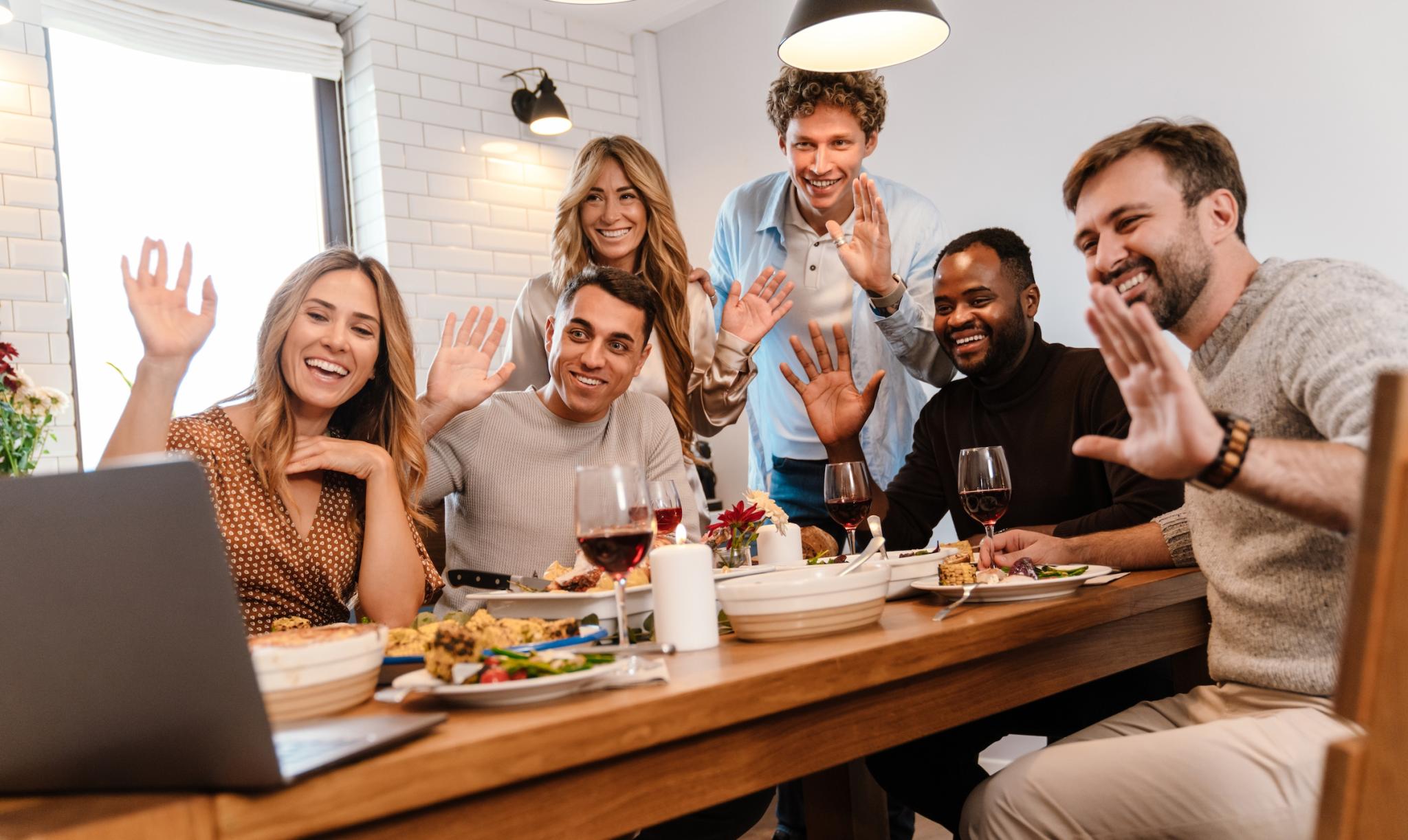 a group of friends zooming with a computer over thanksgiving feast