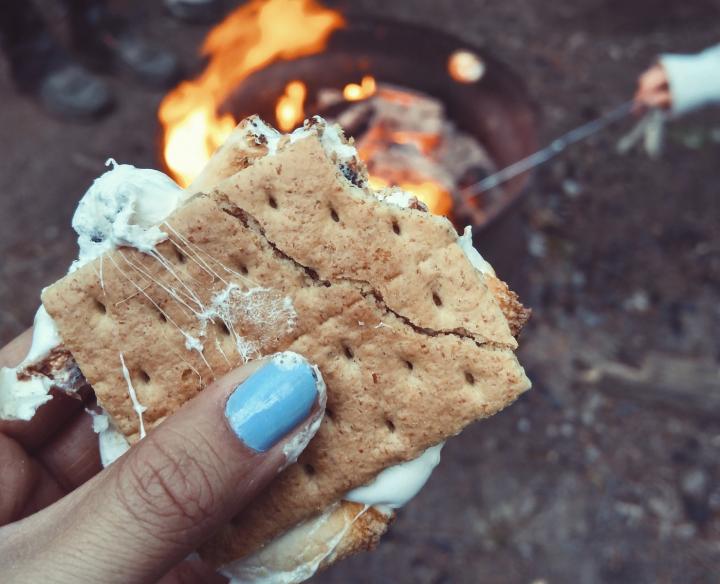 woman's hand with blue nails holding a smore