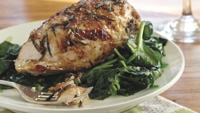rosemary chicken with spinach on a plate for dinner with a fork