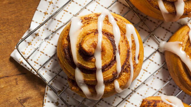 big oversized cinnamon roll with frosting on it cooling on a rock with a towel underneath it