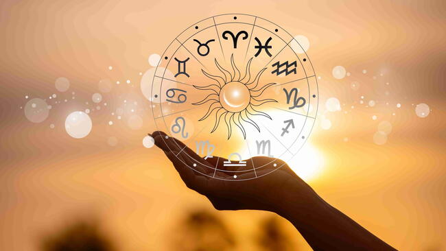 Hand holding a zodiac wheel with symbols for the 12 astrological signs