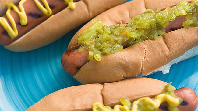 hot dogs with mustard and relish on a blue plate