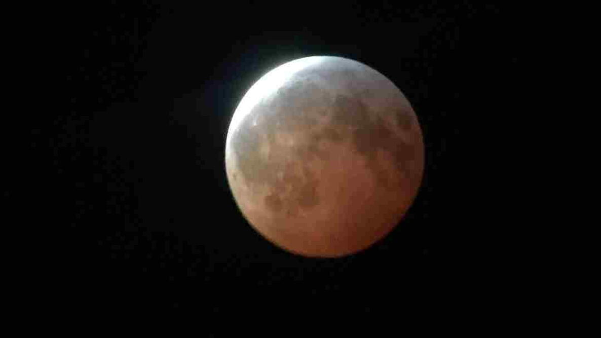 Reddish eclipsed Moon with a bright sliver emerging from Earth’s shadow