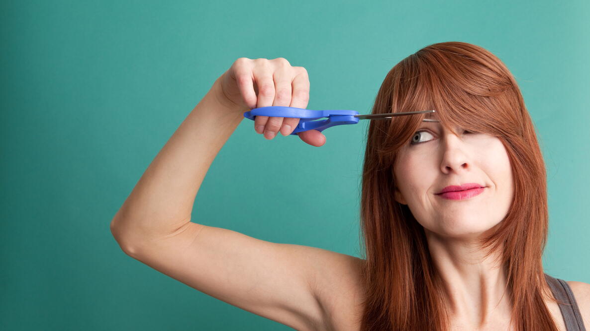 woman cutting her own hair to save money