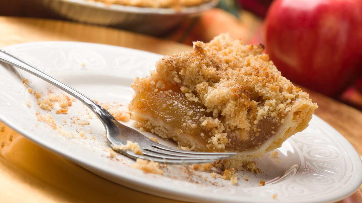 Applesauce Crumb Pie on a white plate with a fork, apple behind it. favorite fall recipe, autumn flavors