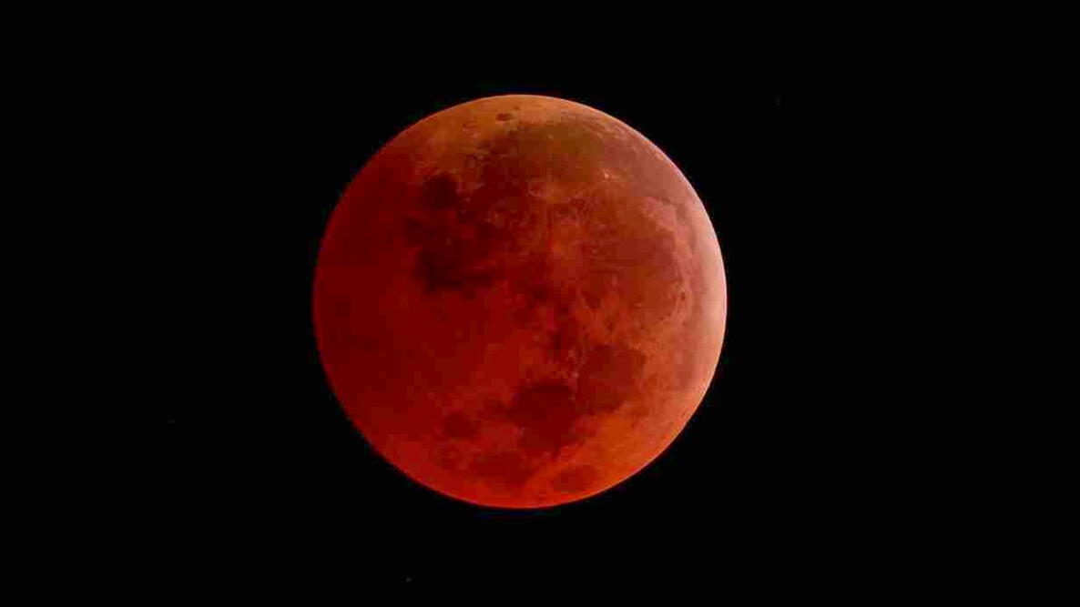 A reddish full Moon during a total lunar eclipse against the black of space