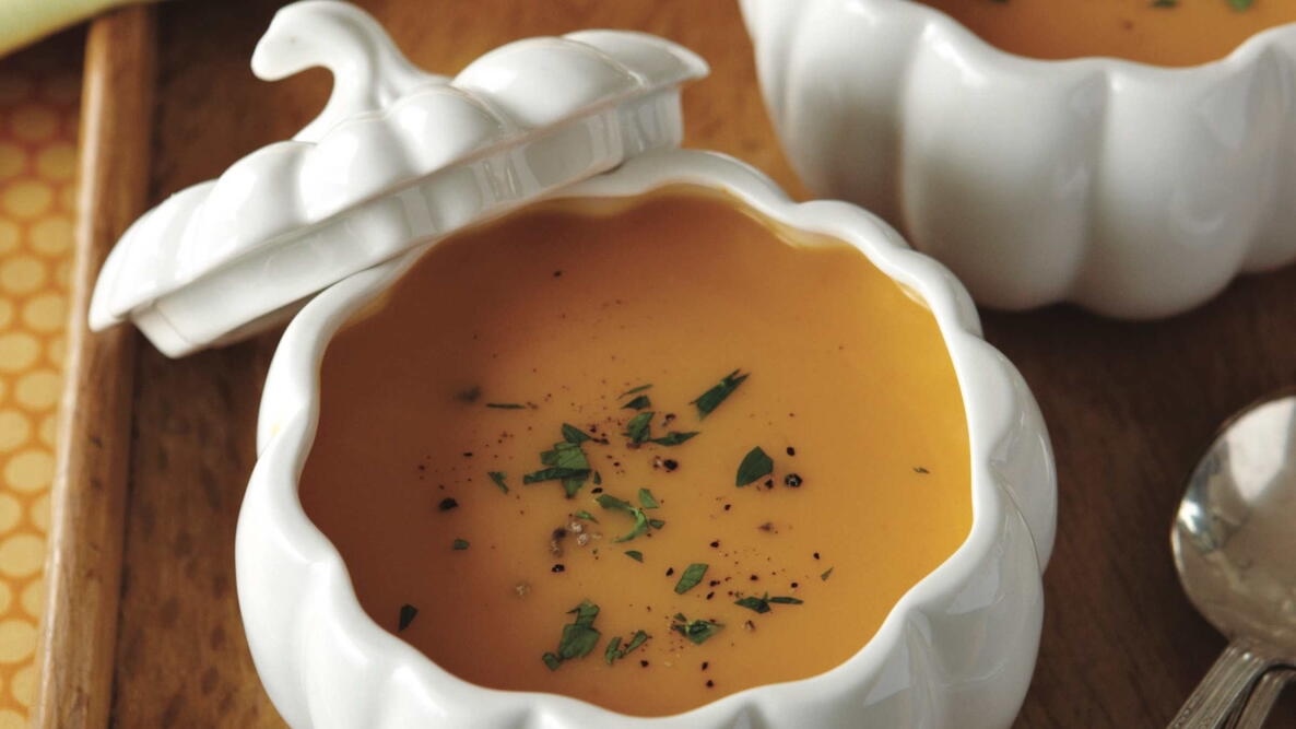 butternut squash soup with fresh herbs in a white pumpkin bowl
