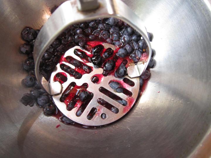 mashing blueberries to make kvass