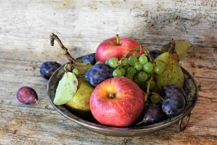 bowl of fruit with apples, plums, pears, and grapes