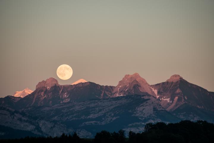 Full moon rises over snowy mountains