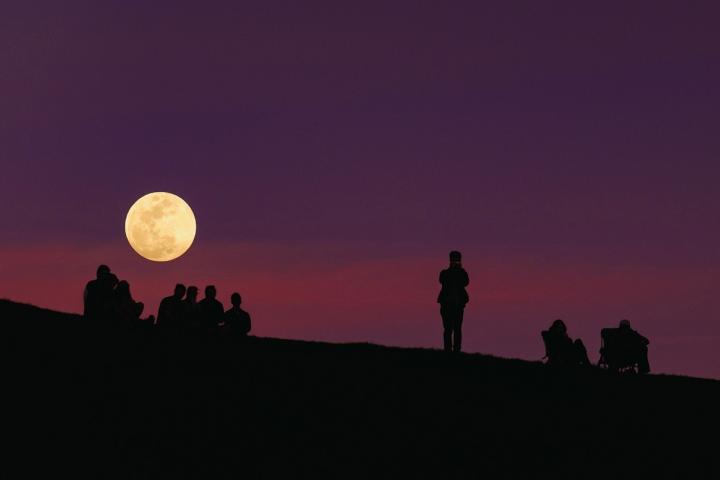 Harvest moon with people standing in front